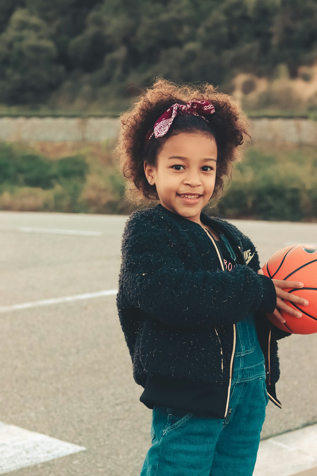 a young girl holding a basketball on a basketball court